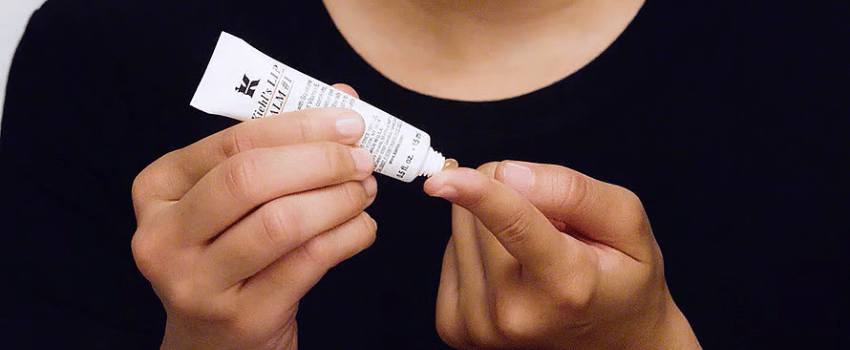 A person holding a Kiehl's free lip balm, representing a Kiehl's birthday gift.